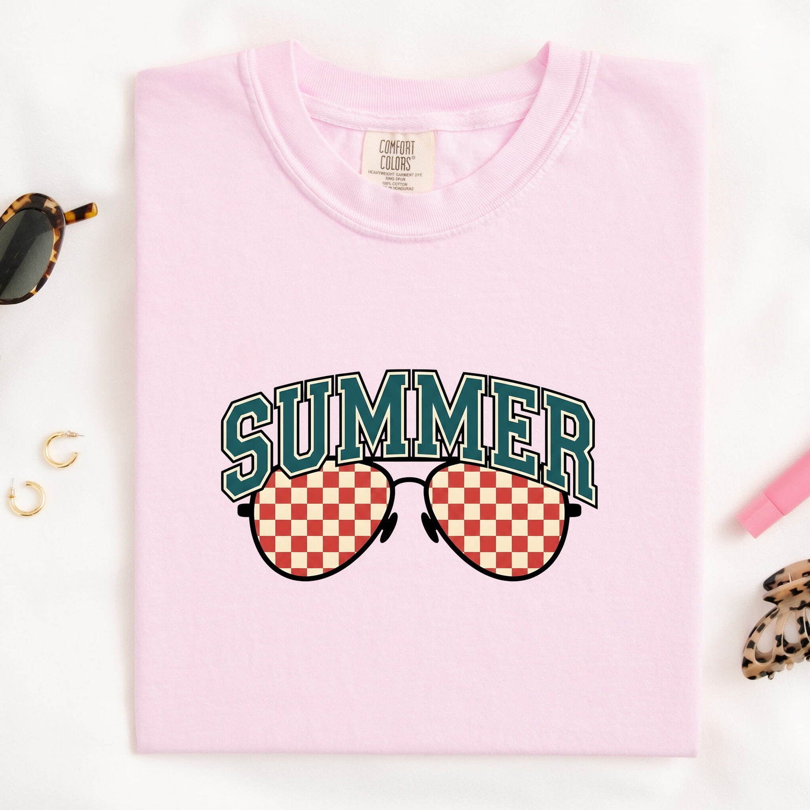 Blossom colored Comfort Colors 1717 t-shirt with 'SUMMER' and sunglasses graphic folded on a white background.