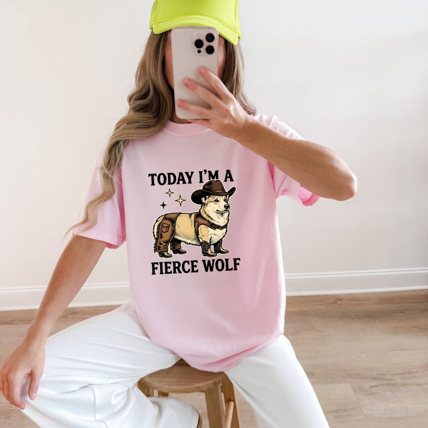 Woman wearing a Blossom Comfort Colors 1717 t-shirt with a corgi graphic and funny text, sitting on a wooden stool.