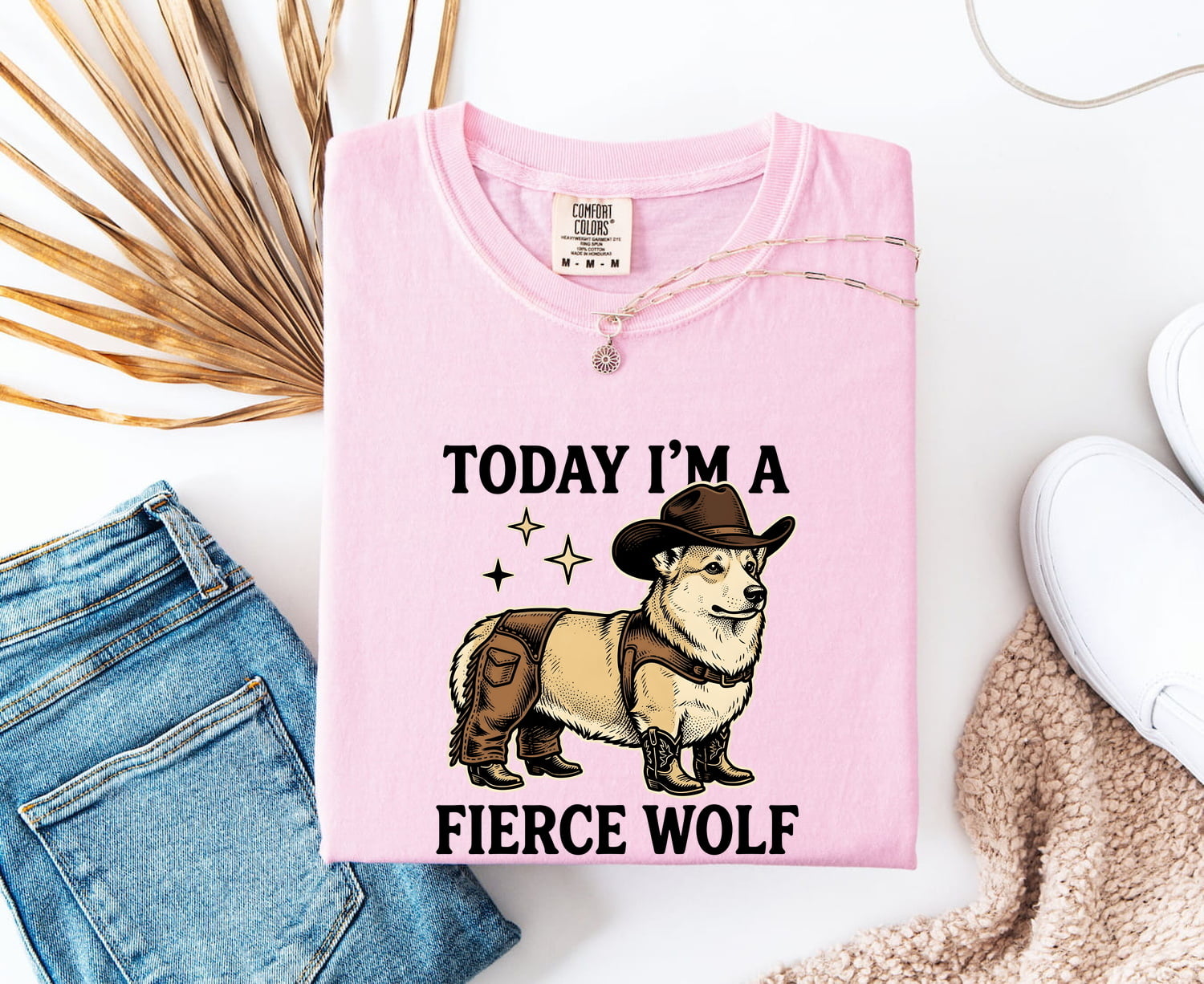 Blossom colored Comfort Colors 1717 t-shirt with a graphic of a corgi in a cowboy hat and text 'Today I'm a fierce wolf' on a white surface with jeans and a shoe.