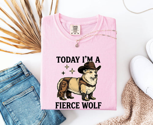 Blossom colored Comfort Colors 1717 t-shirt with a graphic of a corgi in a cowboy hat and text 'Today I'm a fierce wolf' on a white surface with jeans and a shoe.