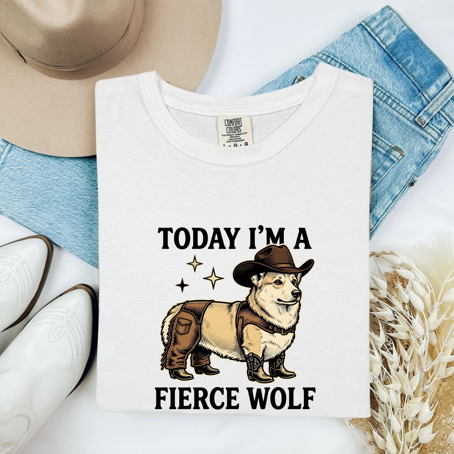 White Comfort Colors 1717 t-shirt with a graphic of a corgi wearing a cowboy hat and text 'Today I'm a Fierce Wolf' on a white background with denim, boots, and a hat.