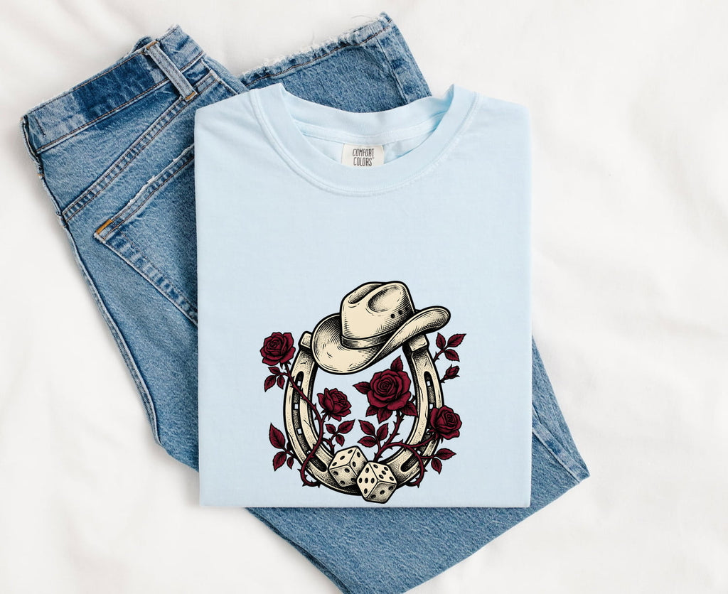 Chambray Comfort Colors 1717 t-shirt with cowboy hat, roses and horseshoe design, folded on jeans