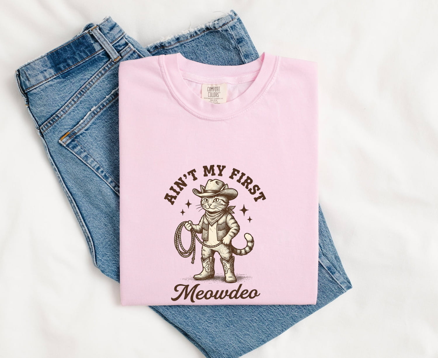 Blossom colored Comfort Colors 1717  t-shirt with funny cat graphic and text folded on jeans
