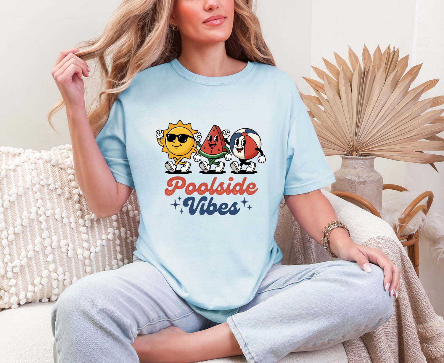 Woman wearing a chambray Comfort Colors 1717 t-shirt with 'Poolside Vibes' graphic design, sitting on a couch