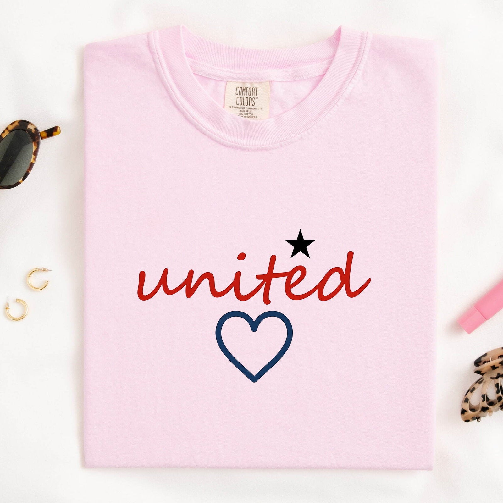Blossom Comfort Colors 1717 t-shirt with 'united' text and heart design, folded on a white background