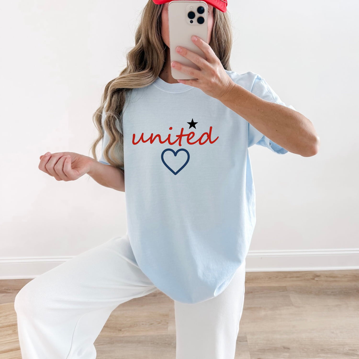 Woman wearing a Chambray Comfort Colors 1717 t-shirt with 'united' and a heart design, taking a mirror selfie.